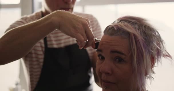 代替クールなヘアサロン 美容室で働く白人男性の美容師の近くのサイドビュー スローモーションで白人女性の髪を切断 — ストック動画
