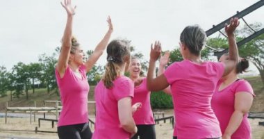 Acemi birliğinde egzersiz yapan, grup halinde beşlik çakan ve ağır çekimde kutlama yapan mutlu çoklu etnik arkadaş grubunun yan görüntüsü.