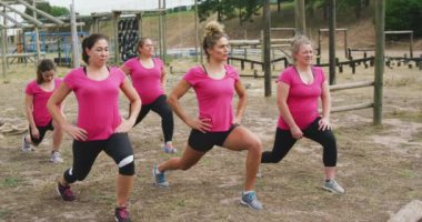 Acemi birliğinde antrenman yapan, ağır çekimde esneme hareketleri yapan çok ırklı mutlu bir kadın grubunun yan görüntüsü.