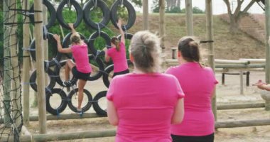 Çok ırklı, mutlu bir arkadaş grubunun acemi birliğinde egzersiz yapması, lastiklere tırmanması ve yavaş çekimde koşması.