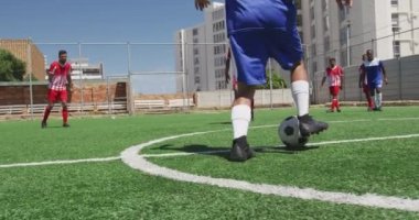 Çok ırklı erkek futbol oyuncularından oluşan bir grubun arka plan görüntüsü. Takım elbisesi giyiyorlar, güneşin altında bir spor sahasında antrenman yapıyorlar, maç yapıyorlar, topa vuruyorlar, ağır çekimde oynuyorlar.