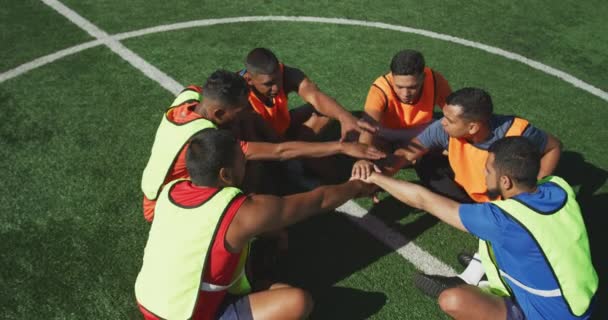 多民族男性足球运动员身穿运动服 身穿彩色围裙 在阳光下的运动场上训练 手执堆叠 动作缓慢 高视角 — 图库视频影像