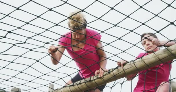 两个白人女人喜欢一起在训练营中锻炼 在攀爬架上爬网 动作缓慢的低角度侧视图 — 图库视频影像