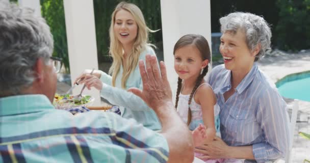 一个多代白人家庭在花园共度时光 坐在一张桌子旁边 一个老人和他的孙女高高兴兴 慢吞吞地坐在旁边 从侧面看这个多代白人家庭 — 图库视频影像