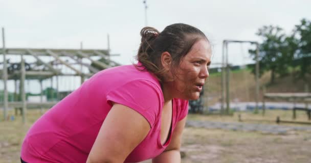 一个疲惫的白种人女人穿着一件粉色T恤 站在新兵训练营 训练后休息 深呼吸 擦拭额头 动作缓慢 侧视全景 — 图库视频影像