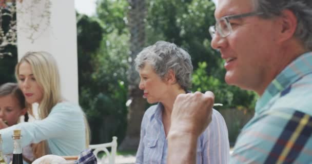 在一个几代白人家庭在花园里共度时光 坐在桌旁 慢吞吞地谈着话 笑了笑的侧观近景 — 图库视频影像