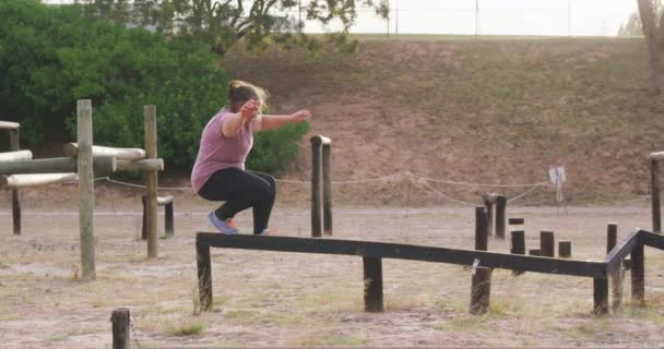 木製の梁に沿って スローモーションで運動を楽しんでいる白人女性の側面図 — ストック動画