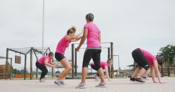 一个快乐的多种族女性群体的侧面视图 她们喜欢一起在训练营中锻炼 一起打嗝 在白人女教练的注视下 都穿着粉色T恤 动作缓慢 — 图库视频影像