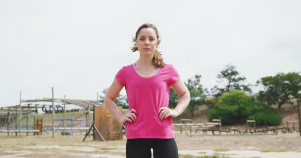 一个白种人女人站在新兵训练营 双手托着臀部 身穿粉色T恤 慢动作的画像 — 图库视频影像