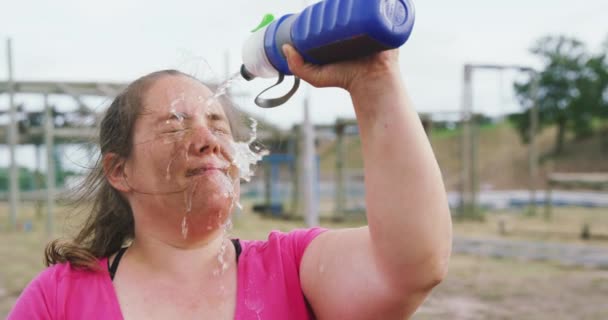 ブートキャンプでピンクのTシャツを着て疲れコーカシア人女性の側のビューを閉じる 彼女の顔にボトルから水を注ぎ 訓練後に自分自身をリフレッシュ スローモーションで — ストック動画