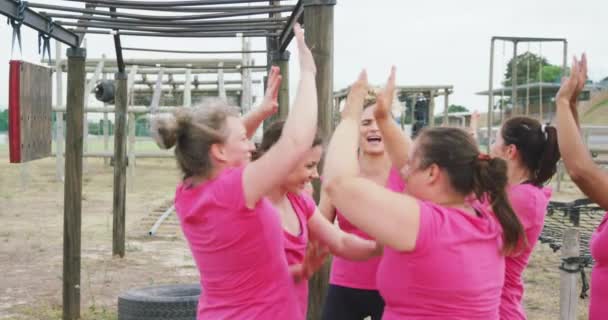 ブートキャンプで一緒に運動を楽しんでピンクのTシャツを着ている女性の友人の幸せな多民族グループのサイドビュー 笑顔と高い5 トレーニング後に祝う スローモーションで — ストック動画
