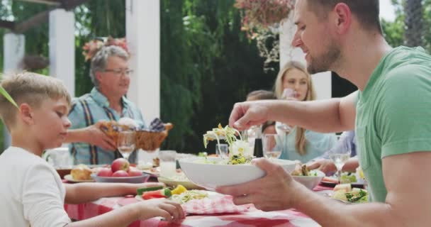 즐거운 시간을 보내고 정원에 음식이 식탁에 남자가 샐러드를 천천히 움직이고 — 비디오