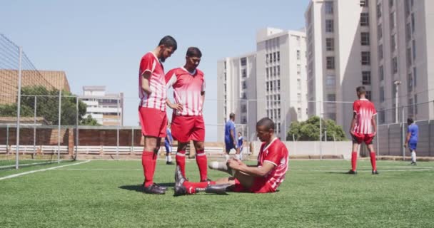 多种族男性足球运动员穿着队服 在阳光下的运动场上训练 一名残疾运动员穿着假腿 一名没有手部慢动作的运动员的侧视图 — 图库视频影像