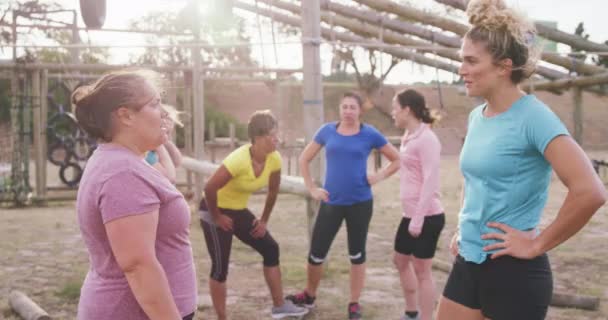 二つの幸せな白人女性のサイドビュー笑いと拳バンピング バックブートキャンプで一緒に運動を楽しんでいる女性の友人の多民族グループと トレーニング後のリラックス スローモーションで — ストック動画
