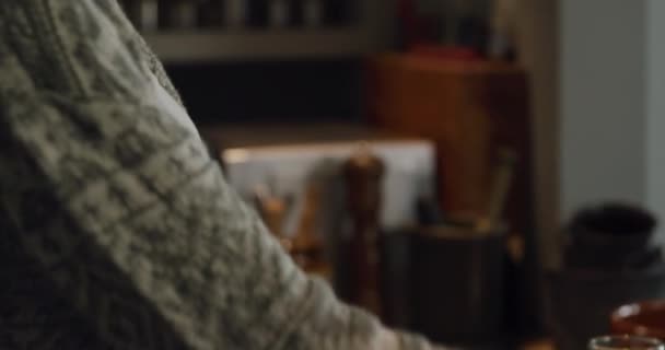 Vue de côté gros plan d'un homme métis et d'une femme caucasienne appréciant le temps passé ensemble à la maison, debout dans leur cuisine, la femme versant du jus d'orange dans les verres .