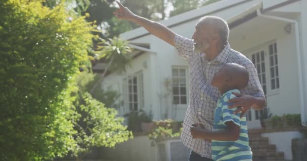 一个年长的混血种族男子在花园里玩得很开心 抱着孙子 在阳光灿烂的日子缓慢地举手投足 — 图库视频影像
