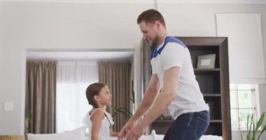 Beyaz bir adamın yan görüntüsü. Dairede eğlenen, kızıyla zıplayan, ağır çekimde kaldıran beyaz bir adam.