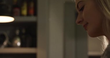 Uzun sarı saçlı, spatula kullanan, mutfakta duran, kahvaltıyı hazırlayan, kızartma tavasında kızarmış yumurta yapan beyaz bir kadının yan görüntüsü..