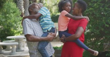 Çok nesilli, çok ırklı bir ailenin bahçede iyi vakit geçirmesini, güneşli bir günde, yavaş çekimde kucaklaşmasını, kucaklaşmasını ön planda tutmak.