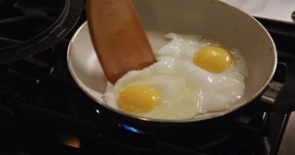 キッチンに立ち 朝食を準備し フライパンで目玉焼きを作る へらを使用して人の高い角度のビューの中央部 — ストック動画