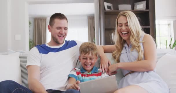 一个白人家庭享受他们在公寓里的时光 坐在沙发上 拿着一个数字平板电脑 看着它 慢吞吞地 — 图库视频影像