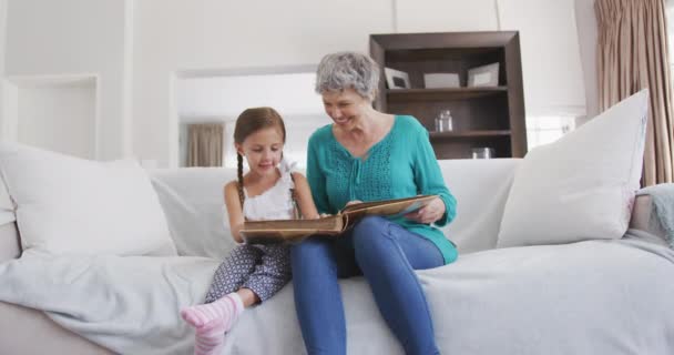 彼女の孫娘とソファに座って家族の写真を見てスローモーションで彼女の時間を楽しんでいる上級白人女性の正面図 — ストック動画