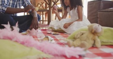 Afrika kökenli Amerikalı bir adam ve melez kızının evde birlikte vakit geçirmesini oturma odasında oturup oyuncak bebek partisi vermesini ağır çekimde kadeh kaldırmasını izlemek.