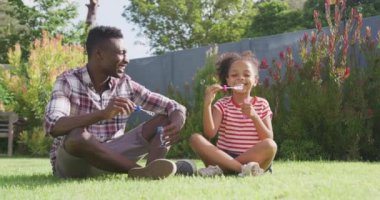 Afrika kökenli Amerikalı bir adam ve melez kızı bahçede birlikte vakit geçiriyorlar, çimenlerin üzerinde oturmuş, köpükler saçıyorlar, yavaş çekimde gülümsüyorlar.