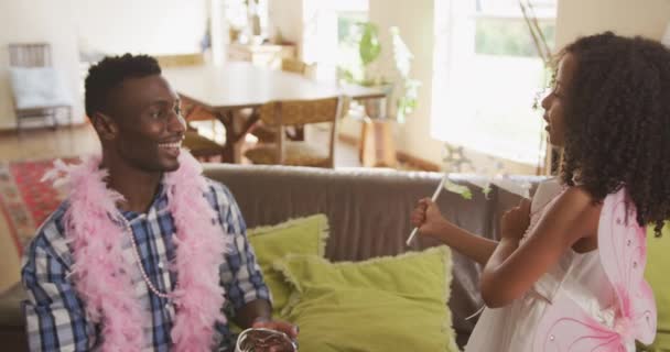 一个非裔美国人和他的混血女儿在家里共度时光 一个穿得像仙女的女孩正在向她的父亲挥着魔杖 缓缓地挥着粉红羽毛 在镜头前大放异彩 — 图库视频影像