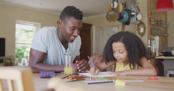 アフリカ系アメリカ人の男と彼の混合レースの娘のフロントビュー一緒に家で時間を楽しんで テーブルのそばに座って 女の子が描画され 男が見ている スローモーションで — ストック動画