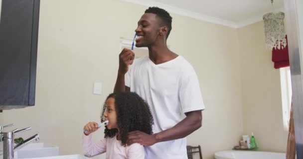 アフリカ系アメリカ人の男性と彼の混合レースの娘の側のビュー一緒に家で時間を楽しんで 歯をブラッシング 一緒に楽しみ スローモーションで — ストック動画