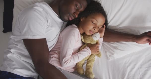一个美国黑人男子和他的混血儿在家里共度时光 躺在床上 睡在一起 一个女孩抱着一只泰迪熊 动作缓慢 高瞻远瞩 — 图库视频影像