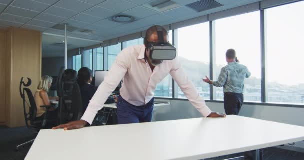 現代のオフィスで働いているアフリカ系アメリカ人ビジネスマンの正面図 Visual Realityヘッドセットを身に着けており 同僚とスローモーションの背景で働いています — ストック動画