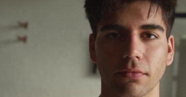 Güneşli bir günde, yavaş çekimde kayıkhanede dikilip kameraya bakan kendine güvenen beyaz bir erkek kürekçinin portresi.