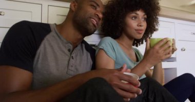 Melez bir çiftin, bir apartmanda birlikte vakit geçirmesinin ön yüzü. Mutfak zemininde oturuyorlar, fincanları tutuyorlar, çay içiyorlar, kucaklaşıyorlar, ağır çekimde. Karantina karantinasında sosyal uzaklık ve kişisel izolasyon