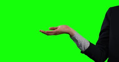 Beyaz elbiseli beyaz bir iş kadınının yan görüntüsü, elini yeşil ekran arka planında bir nesneyi tutar gibi uzatıyor.