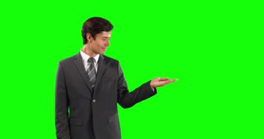 Kafkasyalı bir işadamının şık kıyafetler giyip, yeşil ekran arka planında bir nesneyi tutar gibi elini uzatırken yan görüntüsü.