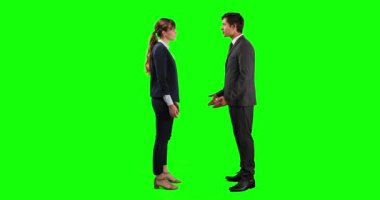 Beyaz bir iş kadını ve işadamının yeşil ekranda gülümseyen ve el sıkışan bir anlaşmayı tartışırken yandan görünüşü.