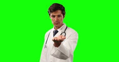 Kafkasyalı bir erkek doktorun, laboratuvar önlüğü ve steteskop giyip, yeşil ekran arka planında bir nesneyi tutar gibi elini uzattığını gördüm.