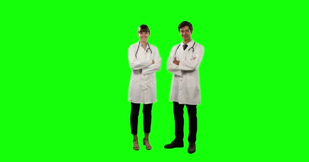 两名身穿实验室外套和听诊器的白人男女医生的前景 他们面带微笑 直视着摄像机 背景是绿色的 — 图库视频影像