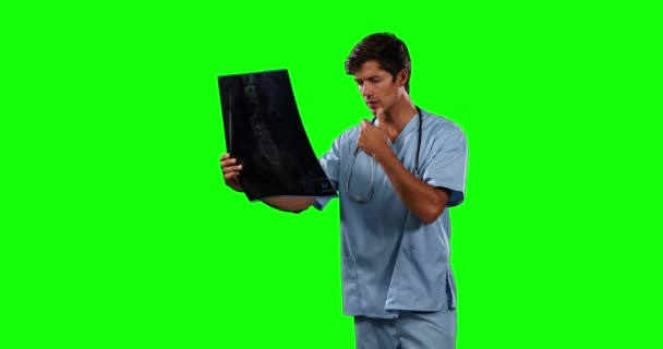青いスクラブと聴診器を身に着けている白人男性医師の側のビュー X線写真を見て 緑の画面の背景に — ストック動画
