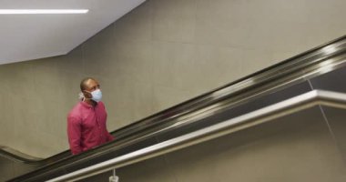 Hava kirliliğine karşı yüz maskesi takan Afro-Amerikalı bir adam, metro istasyonunda yürüyen merdiven kullanarak 19 Coronavirüs 'le boğuştu..