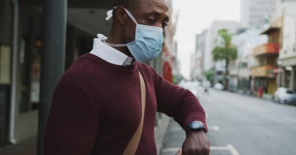 アフリカ系アメリカ人の男性は 大気汚染に対してフェイスマスクを着用し スマートウォッチを使用して 19コロナウイルスをカバーし 日中街中で約 — ストック動画