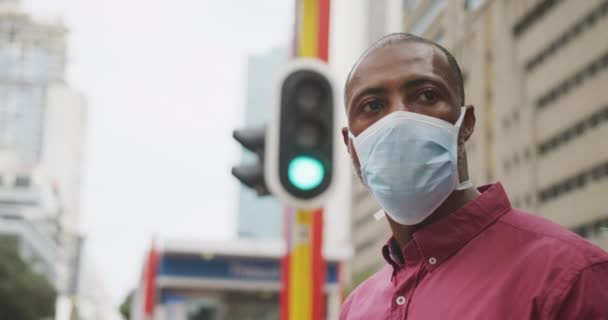 アフリカ系アメリカ人の男性は 大気汚染に対するフェイスマスクを着用し 街を横断し 19コロナウイルスをカバーし 日中街の通りについて — ストック動画