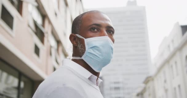 アフリカ系アメリカ人の男性は 大気汚染や海綿状の19コロナウイルスに対してフェイスマスクを着用し 日中街中で約 — ストック動画