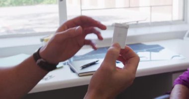 Beyaz bir erkek doktorun pembe gömlek ve steteskop giyen orta kesimi, bir huzurevinde ameliyatta çalışıyor, Coronavirus covid19 salgını sırasında önünde oturan yaşlı beyaz bir kadına tedavi yöntemlerini anlatıyor..