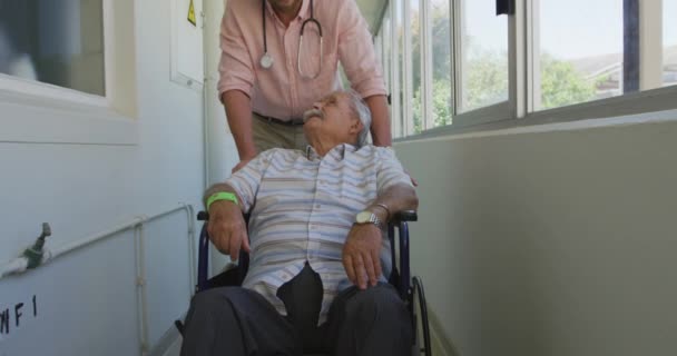 白种人医生在一家养老院工作 与坐在轮椅上的白种人老年男性病人在大流行病中散步和交流 — 图库视频影像