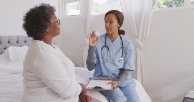 Melez bir ırk hemşiresi tarafından evine ziyaret edilen melez bir kadın. Konuşuyor, sosyal uzaklaşıyor ve kendini karantinaya alıyor. Yavaş çekimde.