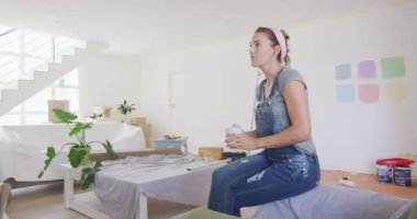 Beyaz bir kadın evinde vakit geçirip evini yeniliyor. Coronavirus covid salgını sırasında karantinaya alınıyor. Kanepede oturuyor ve ağır çekimde içki içiyor.