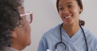 Melez bir ırk hemşiresi tarafından evine ziyaret edilen melez bir kadın. Konuşuyor, sosyal uzaklaşıyor ve kendini karantinaya alıyor. Yavaş çekimde.